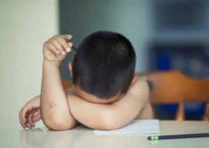 émotion enfant épuisé avec la tête dans les bras